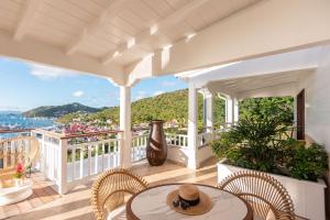 a porch with a table and chairs and a view of the water at Hôtel Barrière Le Carl Gustaf St Barth in Gustavia
