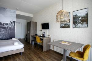 a bedroom with a bed and a table and a desk at Strandhotel Vigilante in Makkum