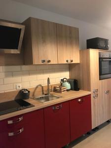 een keuken met rode kasten, een wastafel en een magnetron bij Lovransko Blago in Lovran