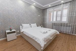 a bedroom with a white bed and a wall at Happy House in Taldykolʼ