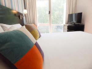 a bedroom with a bed and a tv and a window at Ribera Sur Hotel in Buenos Aires