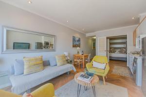 a living room with a couch and chairs and a table at Sea Front Granger Bay Apartment in Cape Town