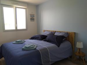 1 dormitorio con 1 cama con sábanas y almohadas azules en Maison de vacances près de la mer à Créances, en Créances