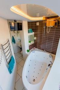 a bathroom with a tub and a tiled wall at Big Jacuzzi , Sauna , Khreshchatyk apartments in Kyiv