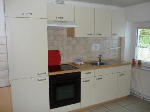 a kitchen with white cabinets and a sink and a stove at Ferienwohnung Angelika und Guenter in Handewitt
