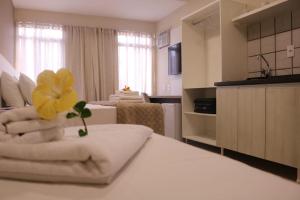 um quarto de hotel com duas camas e uma flor amarela em cima em Caravaggio Praia Hotel em Florianópolis