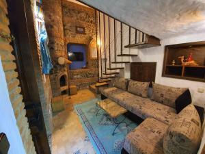 a living room with a couch and a staircase at Riad Gharnata in Chefchaouen