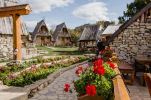 a garden with red flowers on a stone building at Eco Village Nevidio in Pošćenje