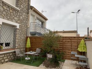 a patio with a table and chairs and a fence at Le Marty in Narbonne