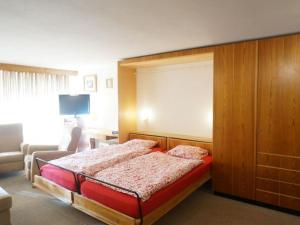 een slaapkamer met een bed met een houten hoofdeinde bij Apartment La Sarine 13 by Interhome in Gstaad