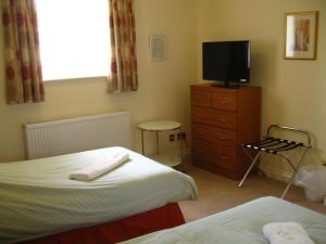 1 dormitorio con 2 camas y un tocador con TV en Simpson's Apartments en Daventry