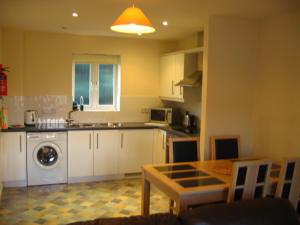 a kitchen with white cabinets and a table in it at Simpson's Apartments in Daventry