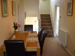 een eetkamer met een tafel en stoelen en een trap bij Simpson's Apartments in Daventry