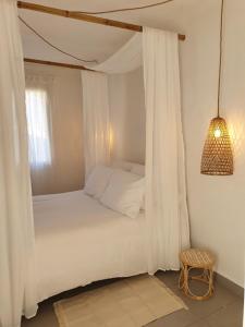 een slaapkamer met een hemelbed en een stoel bij Une Nuit à Bali - Appartement cocooning in Solliès-Toucas