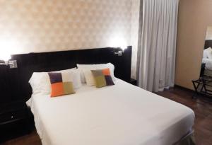 1 dormitorio con 1 cama blanca grande y 2 almohadas en Ribera Sur Hotel en Buenos Aires