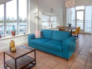 een woonkamer met een blauwe bank en een tafel bij Apartment De Meerparel by Interhome in Uitgeest