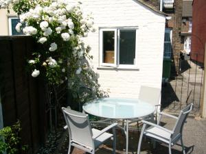 eine Terrasse mit einem Tisch und Stühlen sowie weißen Blumen in der Unterkunft Victoria Road, comfortable 3 bedroom houses with fast Wi-Fi in Sittingbourne