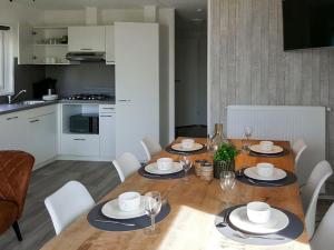comedor con mesa de madera y sillas blancas en Holiday Home Camping Cassandria Bad-1 by Interhome, en Retranchement