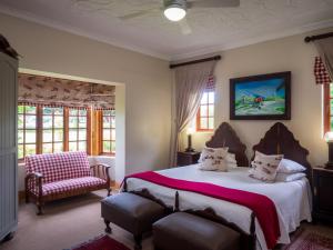 a bedroom with a bed and a chair and windows at Fouriesburg Country Inn in Fouriesburg