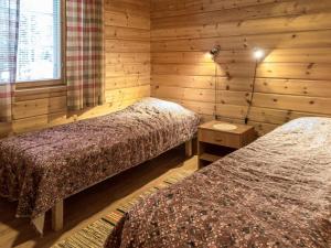 two beds in a room with wooden walls at Holiday Home Lapinkulta b by Interhome in Äkäslompolo