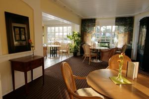 a dining room with tables and chairs and windows at Hotel Villa Verde in Düsseldorf