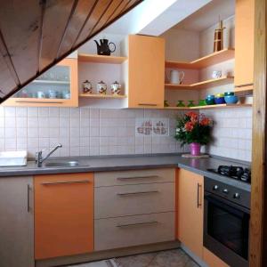 a kitchen with orange and gray cabinets and a sink at Apartment Petra in Mrkopalj