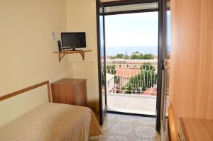 Zimmer mit einem Bett und einer Glasschiebetür mit einem Balkon in der Unterkunft Hotel Virgilio in Tropea