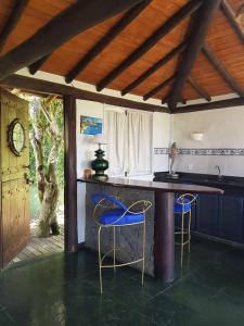 a kitchen with a counter and two blue chairs at Bella Vista Eco Experience in Búzios