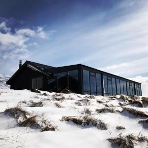 a black house in a snowy field with a building at Hofsstadir - Country Hotel in Hofstaðir