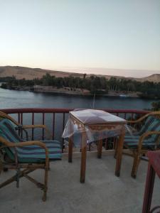 uma mesa e cadeiras numa varanda com vista para um rio em El Prince Guesthouse em Aswan