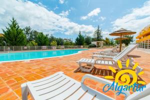 - une piscine avec des chaises longues et un parasol dans l'établissement Royal Cabanas Golf by Algartur, à Cabanas de Tavira