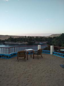 uma mesa e cadeiras numa varanda com vista para a água em El Prince Guesthouse em Aswan