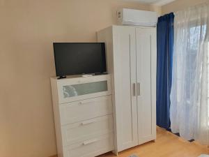 a bedroom with a television and a dresser at Airport Apartman in Vecsés
