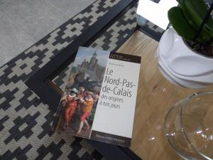 un libro sentado en una mesa junto a un jarrón en Aux Herbes Hautes en Fleurbaix