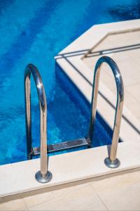 a swimming pool with two metal rails next to the water at Villa Mirjana in Trogir