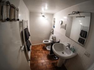 een badkamer met een wastafel, een toilet en een spiegel bij Cozy House in Parma