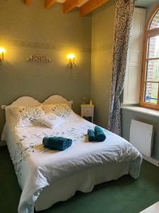 una camera da letto con un letto bianco e asciugamani blu di LE MOULIN DE MERAL a Montsûrs