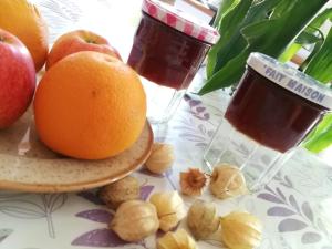 a table with apples and oranges on a table with a drink at La Malinette bio B&B, calme et authenticité in Mâlain