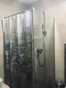 una ducha con cortina de ducha y un bosque. en Milmari Apartman P38 en Kopaonik