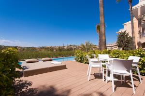 Un patio con mesa y sillas junto a una piscina. en Insotel Cala Mandia Resort, en Cala Mendia