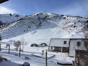 a building in the snow with a snow covered mountain at 2 Appt 4 à 6 pers Val Louron au pied des pistes in Génos
