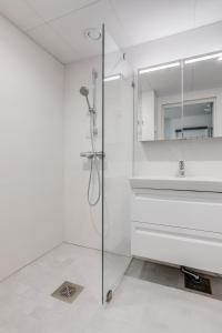 baño blanco con ducha y lavamanos en Tapiola Oak Apartment en Espoo