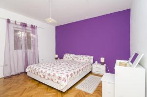 1 dormitorio con cama y pared púrpura en Holiday Home Kim, en Mokošica