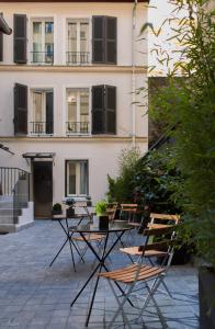 パリにあるホテル ミラボー エッフェルの建物の前にテーブルと椅子付きのパティオ