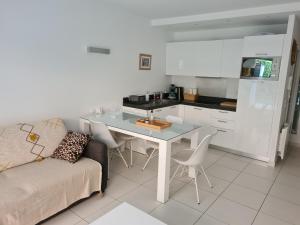 sala de estar con sofá, mesa y cocina en Le Lodge, T2 classé 3 étoiles avec jardin, parking, piscine & mer à 2 pas en Menton