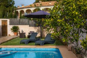 een zwembad met 2 stoelen en een parasol bij Casa Manolo in Cala Ratjada