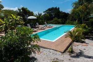 a swimming pool with two chairs and an umbrella at Mangabeira Logde in Ilha de Boipeba