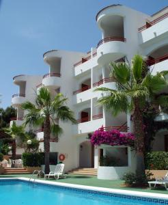 a hotel with a swimming pool in front of a building at Apartamentos Vista Playa I in Cala Blanca