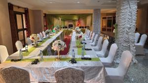 ein langer Tisch mit weißen Stühlen und Blumen darauf in der Unterkunft Hôtel Jouvence International in Jaunde + 18 Fotos