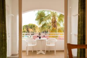 a white table and chairs in a room with a palm tree at Sagitario Vista Playa I Apartamentos in Cala Blanca